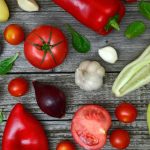 Vibrant fresh vegetables including tomatoes, peppers, and garlic on a rustic wooden surface.